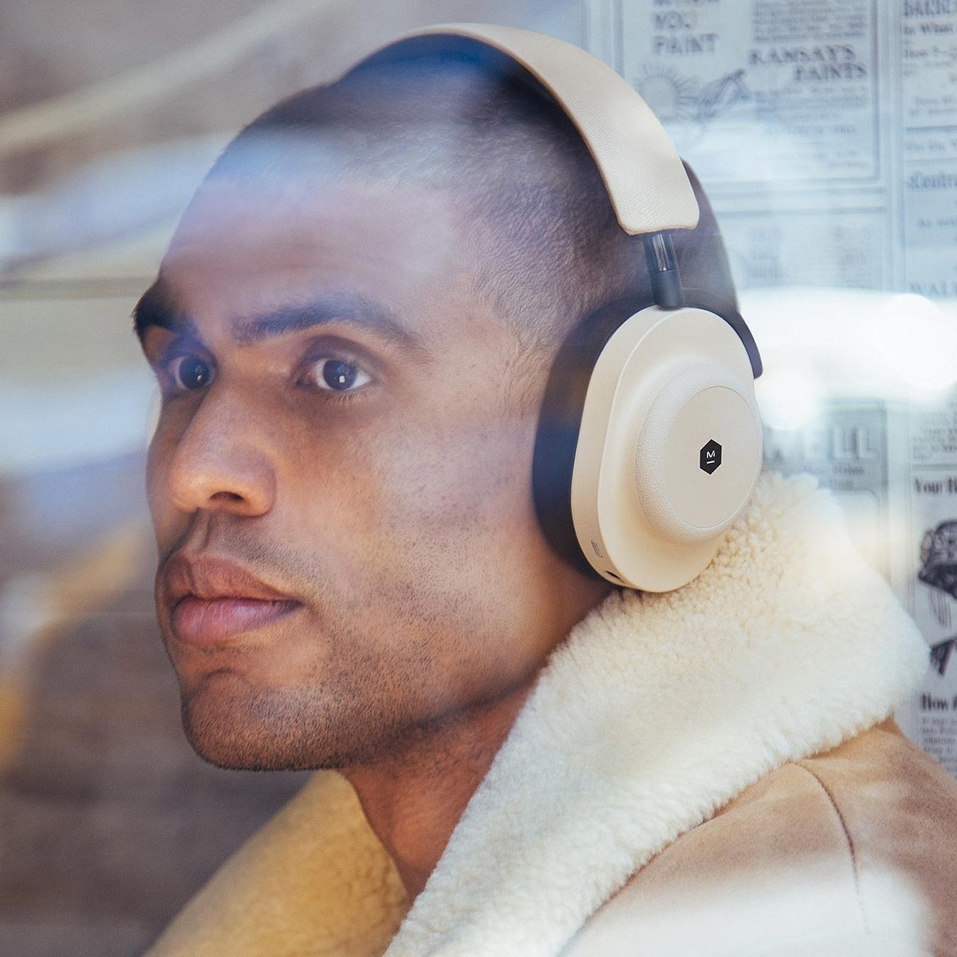 Man in tan coat staring out the window of a cafe wearing sand dune and black MG20 Wireless Gaming Headphones | gallery MG20SD10