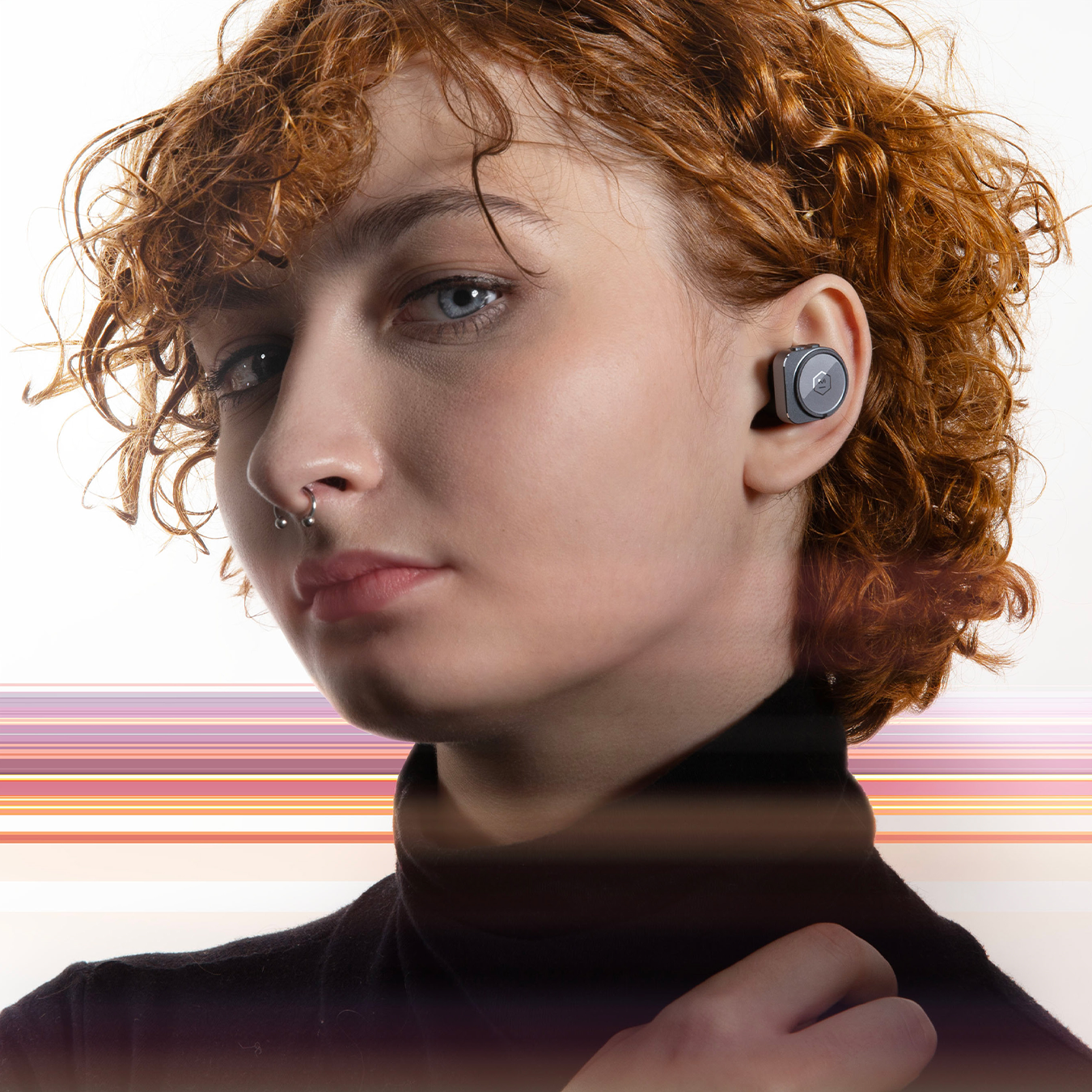 Woman with red hair and black turtleneck wearing gunmetal and black MW09 True Wireless Earphones against a white background with pink stripes | gallery MW09G3