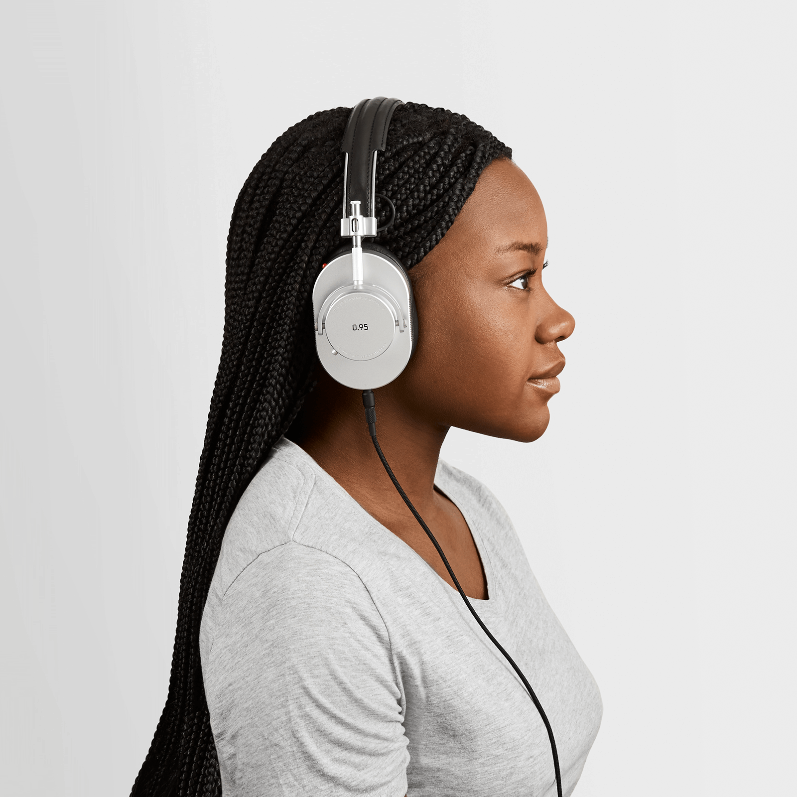 Profile of woman with black hair and a grey v-neck shirt wearing black leather and silver metal MH40 Wireless Headphones with Leica 0.95 on the ear cup and optional 3.5mm audio cable attached  | gallery MH40S-95