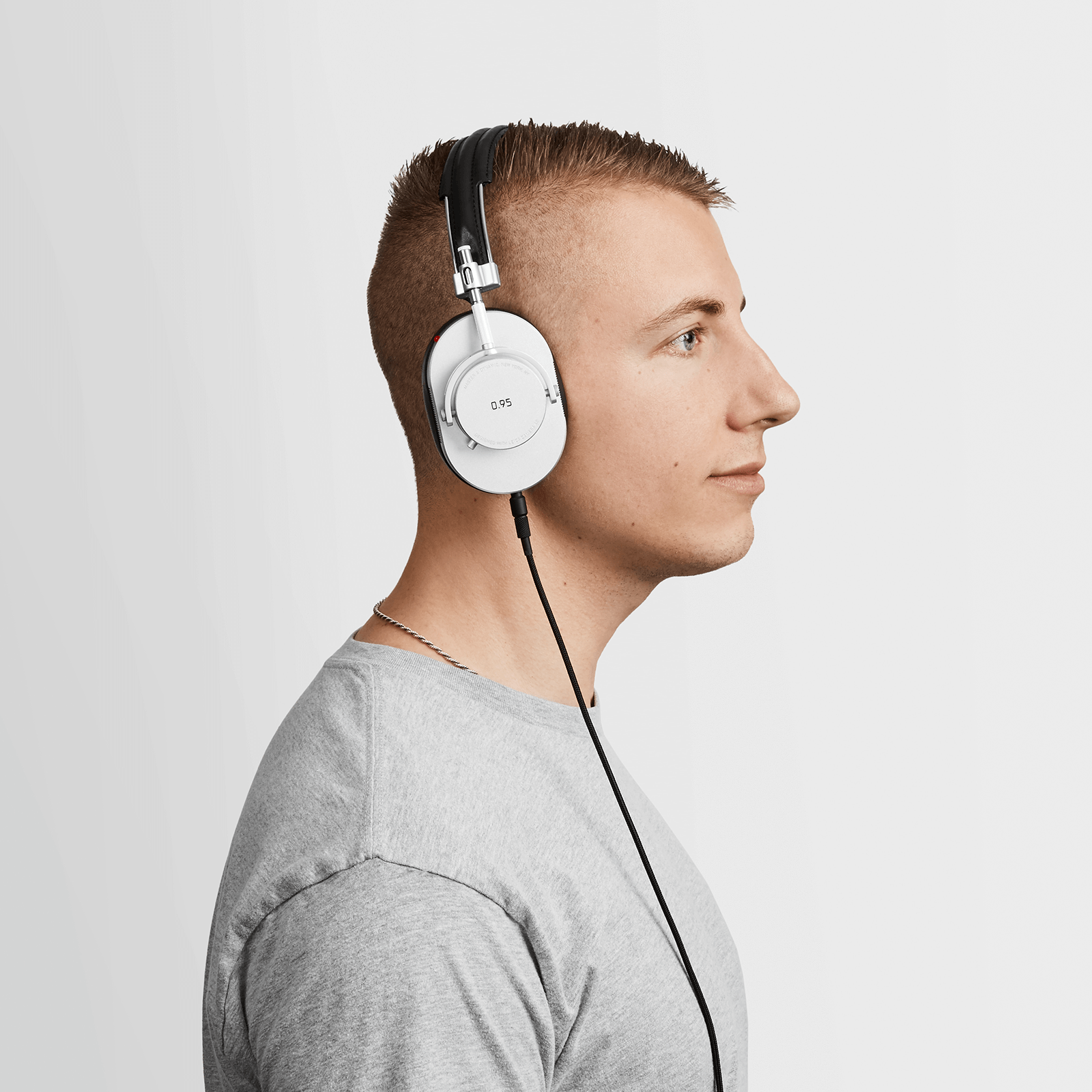 Profile of man with blonde hair and a grey v-neck shirt wearing black leather and metal MH40 Wireless Headphones with Leica 0.95 on the ear cup and optional 3.5mm audio cable attached  | gallery MH40S-95