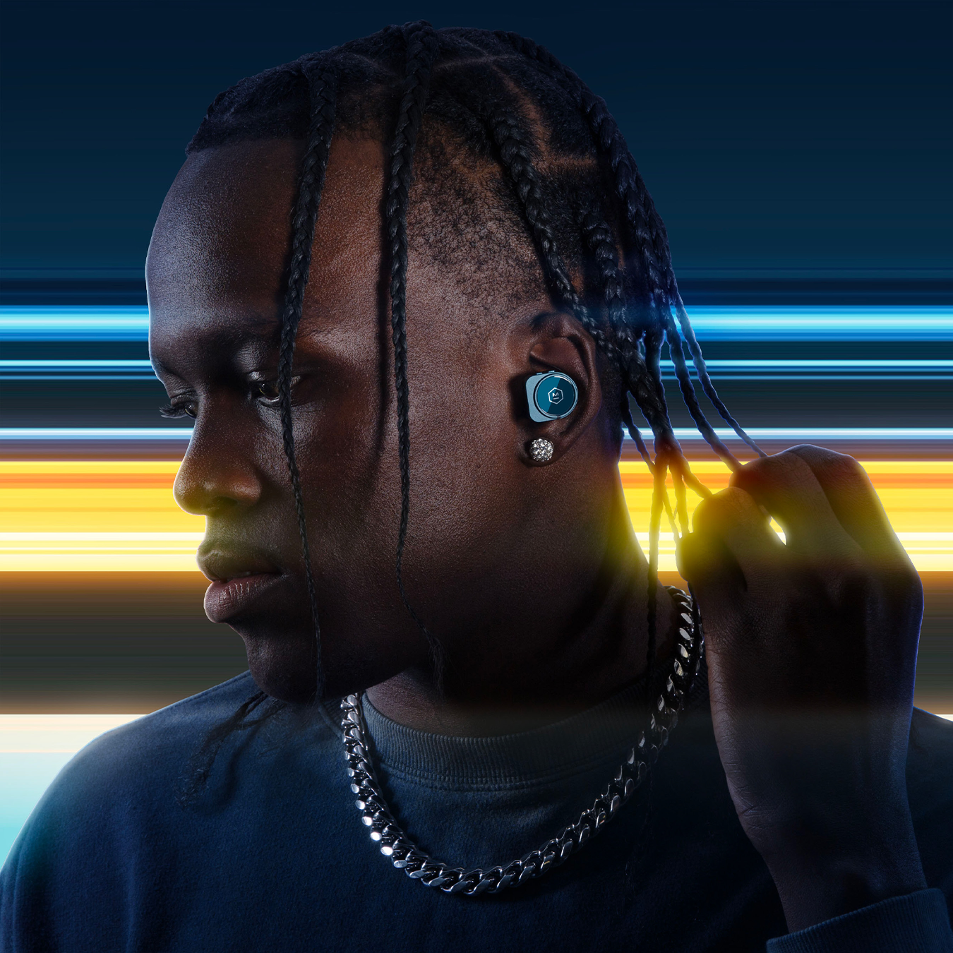 Man with a black t-shirt and silver necklace wearing blue MW09 True Wieless Earphones against a blue and yellow background | gallery MW09BL4