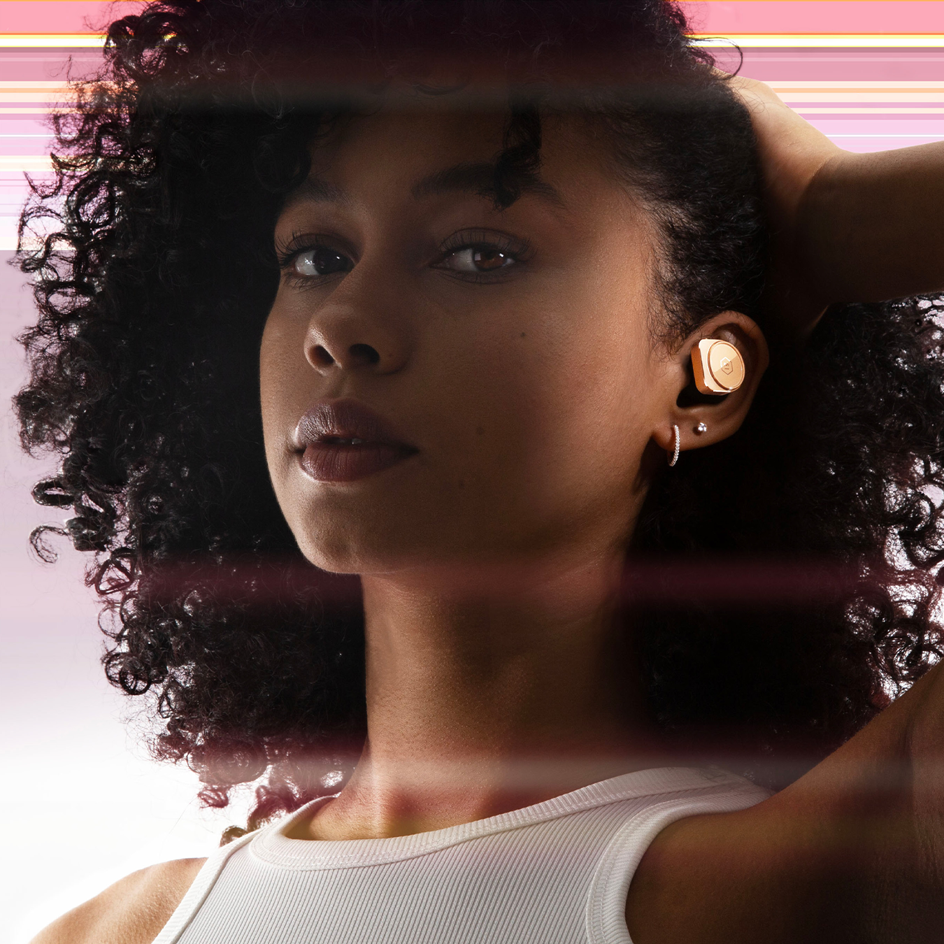 Woman with white shirt and dark hair wearing gold MW09 True Wireless Earphones against a purple and pink background | gallery MW09GD10